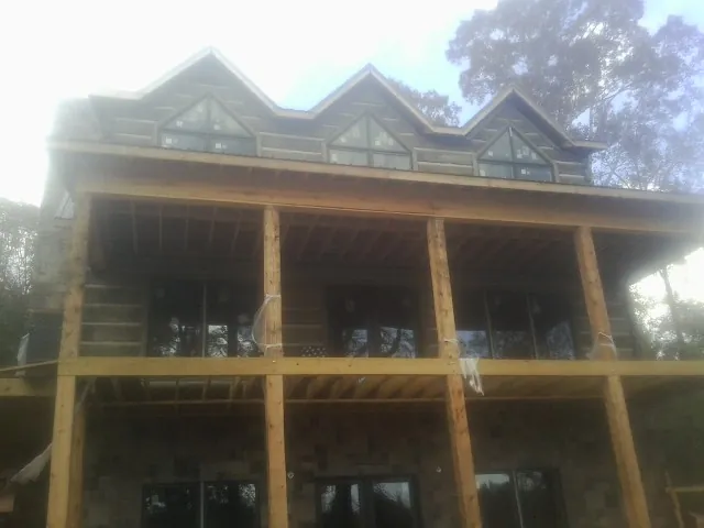 Dormers and porch framing on a large log home under construction — Roof Coating work by our crew in Portsmouth